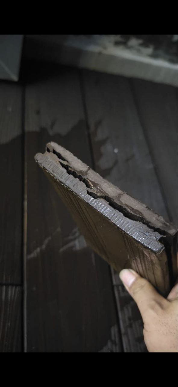 Hand holding a cut section of hollow WPC decking board showing internal chambers